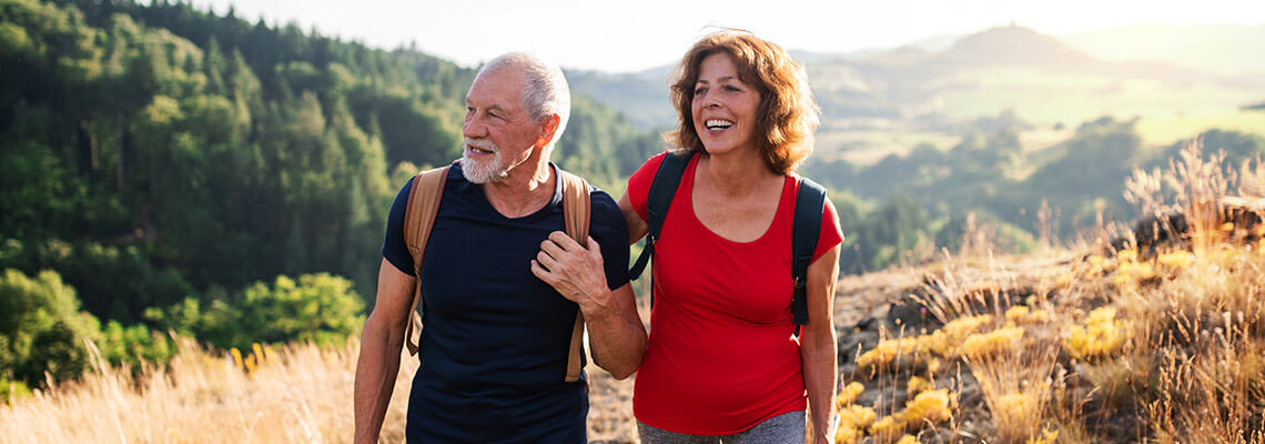Older couple hiking on top of a hill