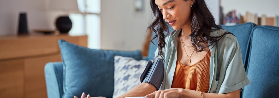 Young woman measuring her own blood pressure with an electronic device at home