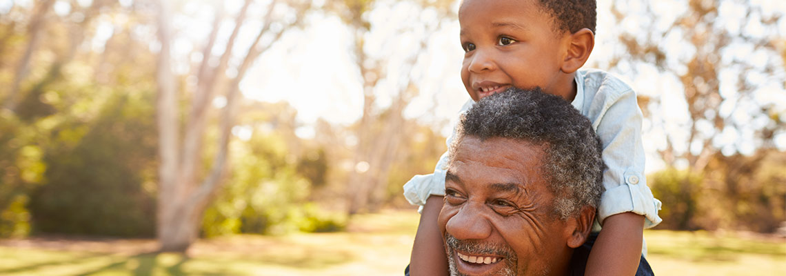 Grandfather carrying grandson in a park