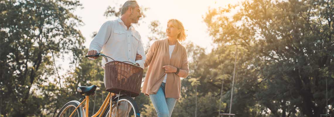Senior couple walking in the park with a bicycle