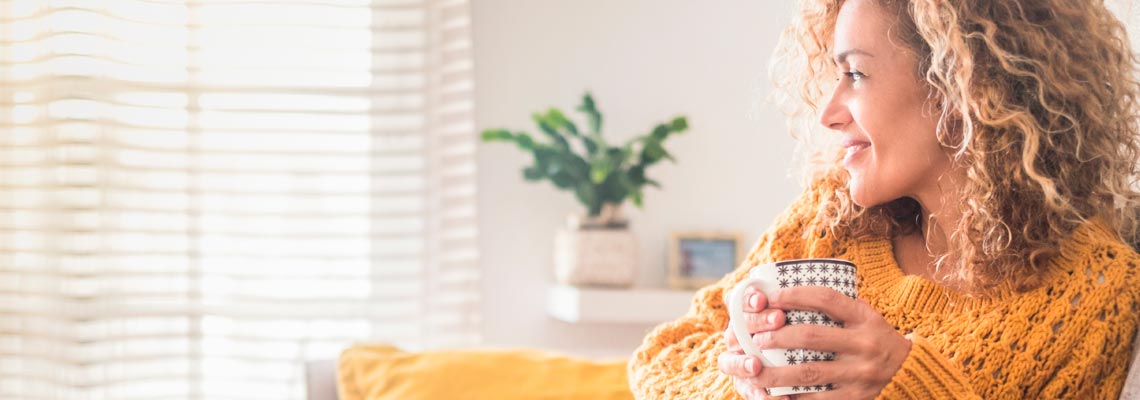 Woman relaxing at home with cup of tea and book