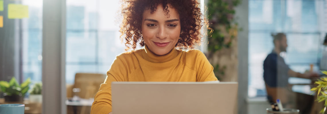 Female with curly hair using laptop in modern office