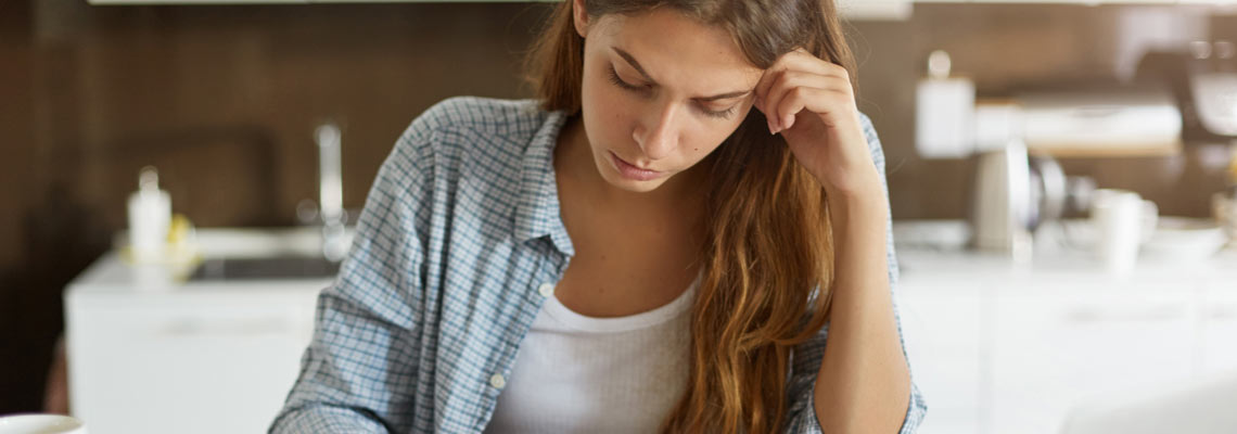 worried young mother feeling stressed while working through finances in kitchen