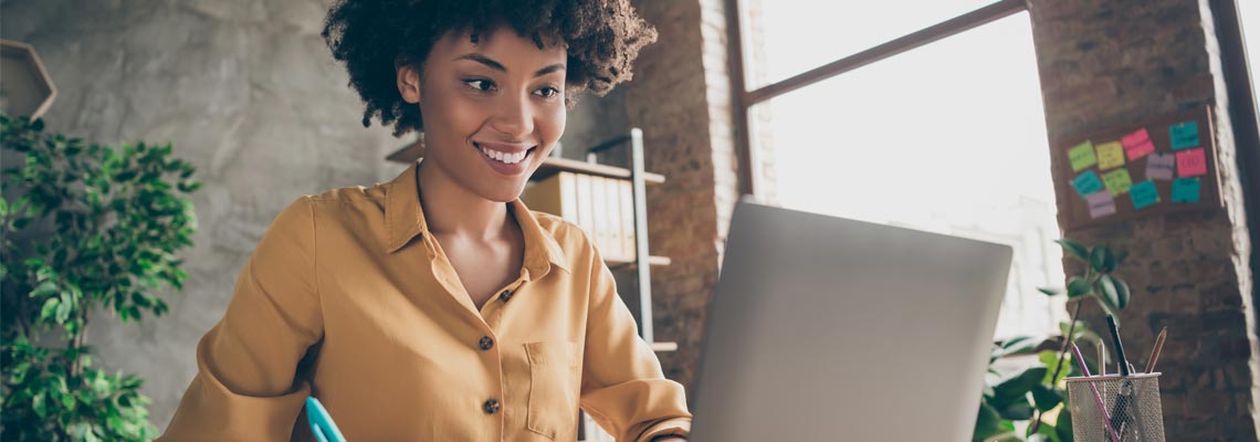 Joyful woman in yellow shirt smiling while writing down notes