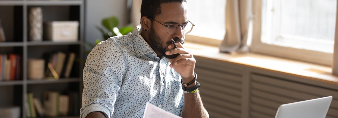 accountant holding documents looking at laptop screen