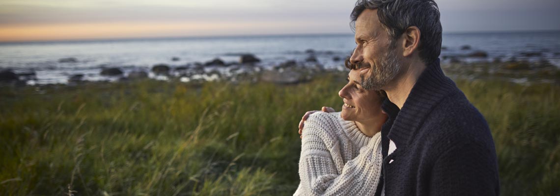 mature couple smiling and looking at  sunset